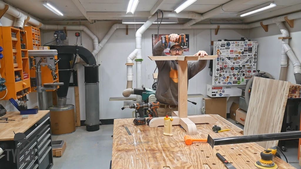 man drilling countersink screw into table pedestal pieces