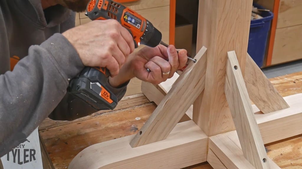 man drilling screw into table brace piece