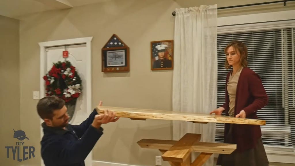 man and woman assembling game table top onto pedestal base piece