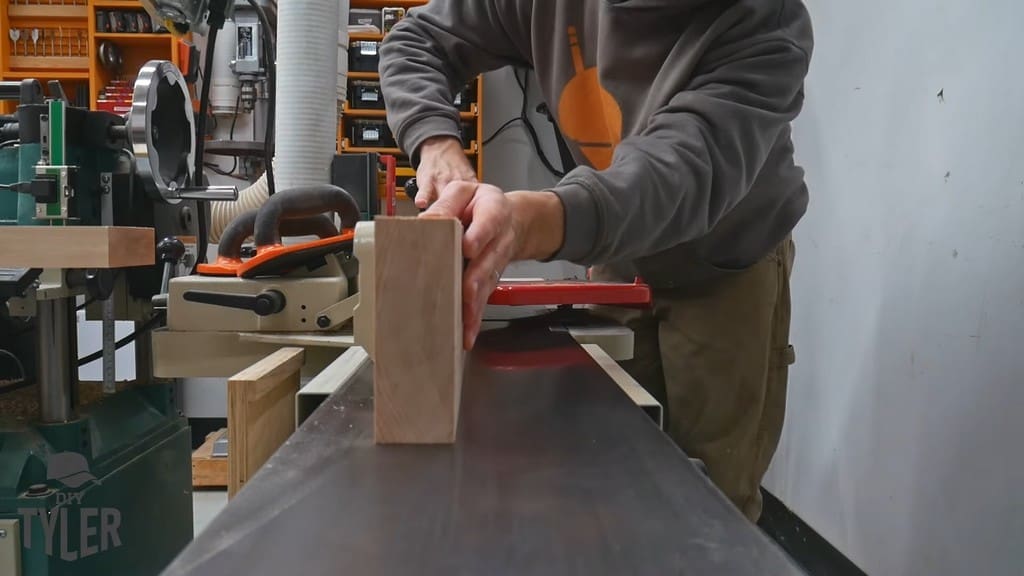 man running maple wood piece through jointer
